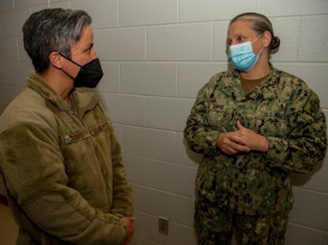 Navy and Air Force members talk in a hallway.