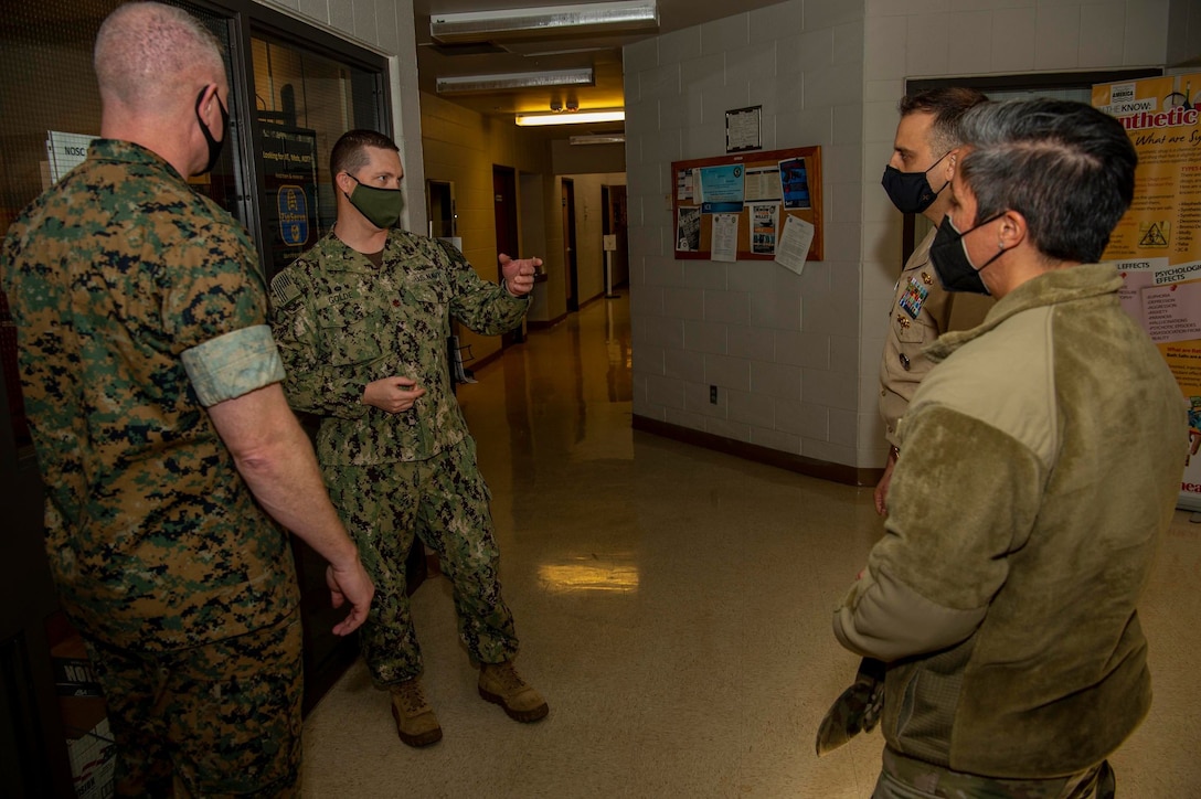Marine Corps, Navy and Air Force members talk in a hallway.