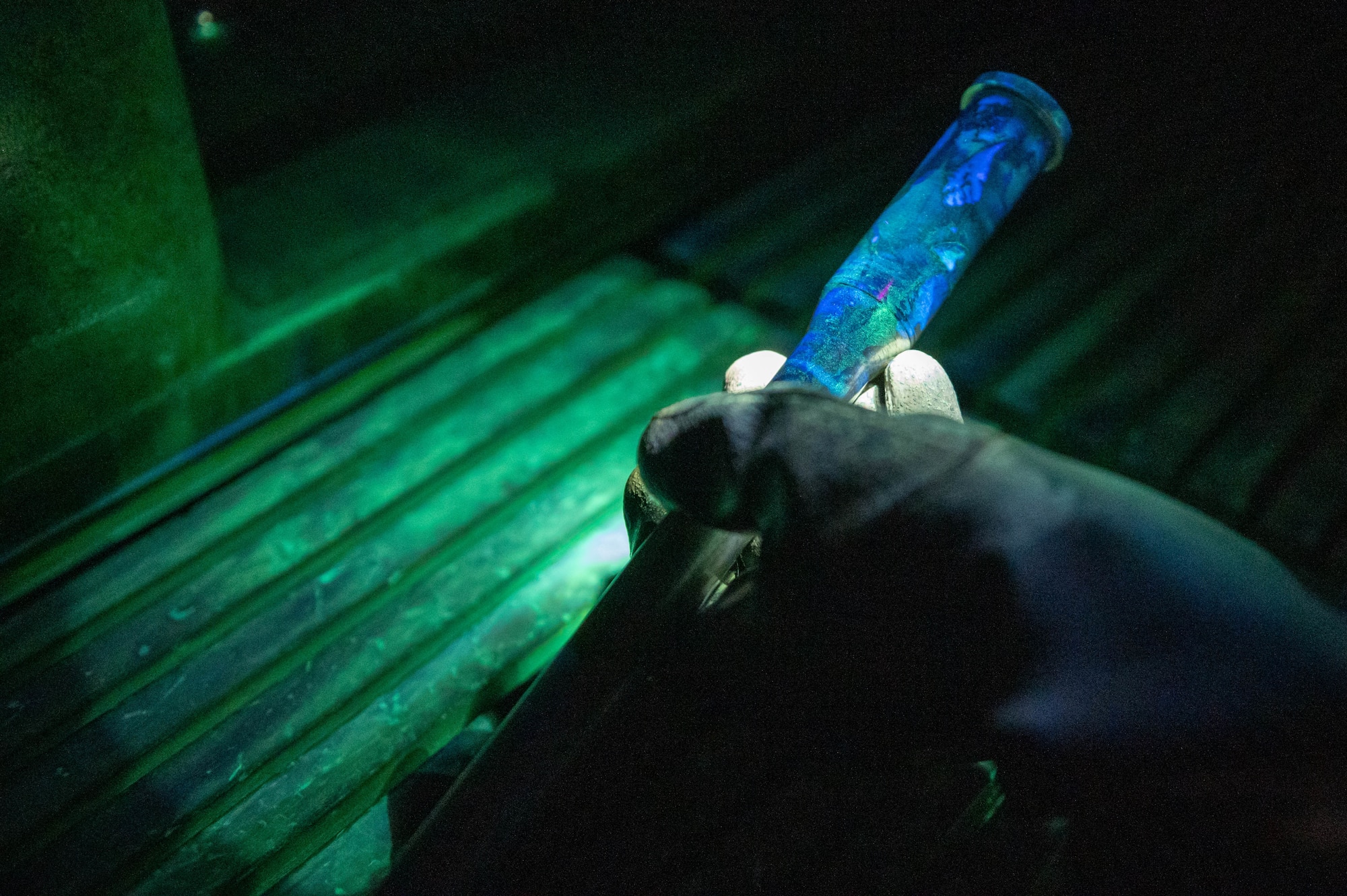 Technician holds a boom fork shaft under a black light.