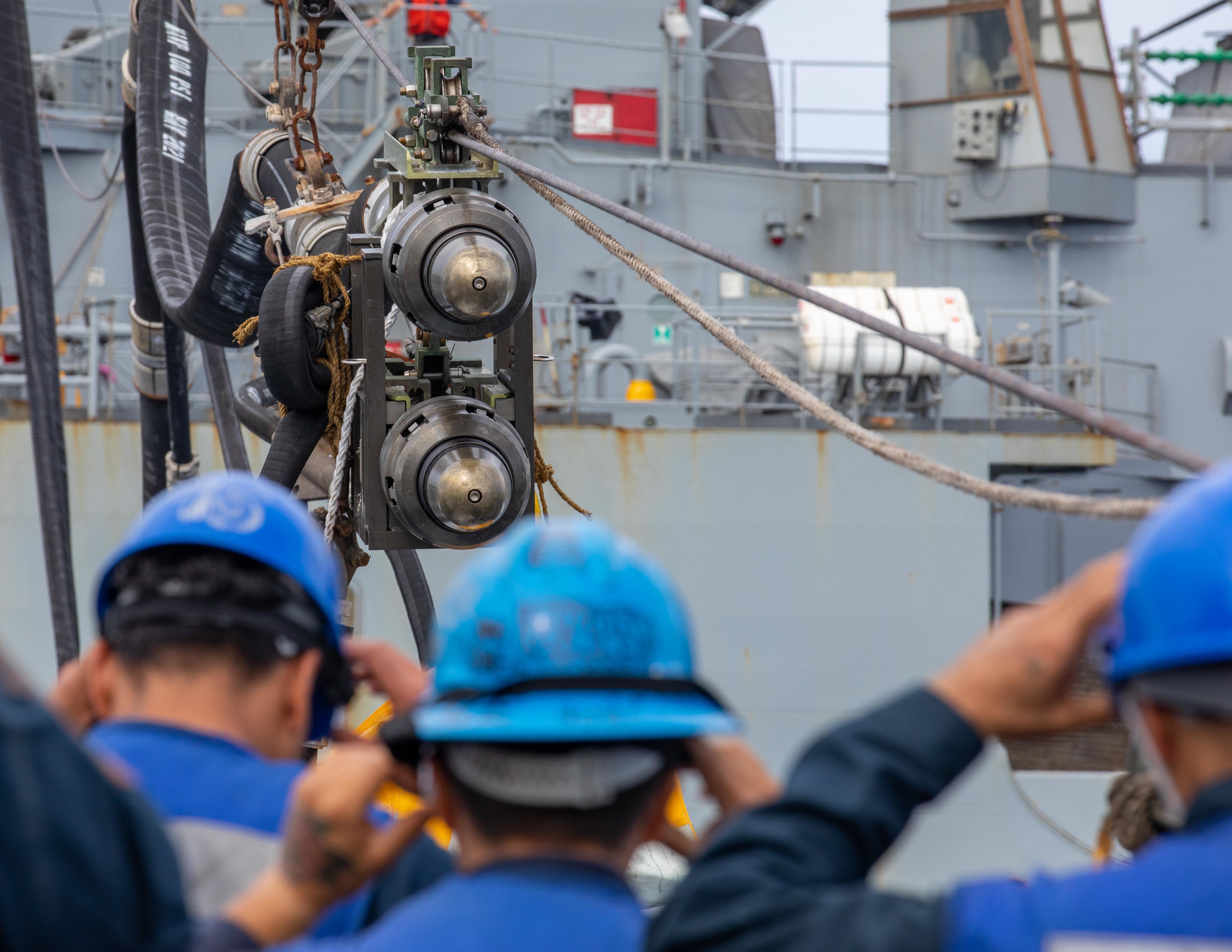 Sailors aboard Arleigh Burke-class guided-missile destroyer USS Dewey (DDG 105) standby to receive a fuel probe from Lewis and Clark-class dry cargo ship USNS Matthew Perry (T-AKE-9).