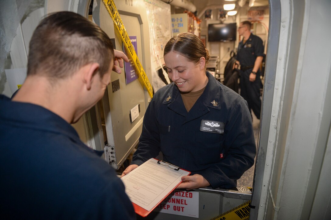 Legalman 1st Class Jessica Smart, right, from Gainesville, Florida, helps Boatswain's Mate 1st Class Nicodemus Beach, from Grand Bay, Alabama, sign paperwork aboard the Nimitz-class aircraft carrier USS Harry S. Truman (CVN 75).