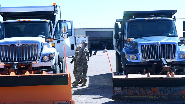 two airman look at a snowplow