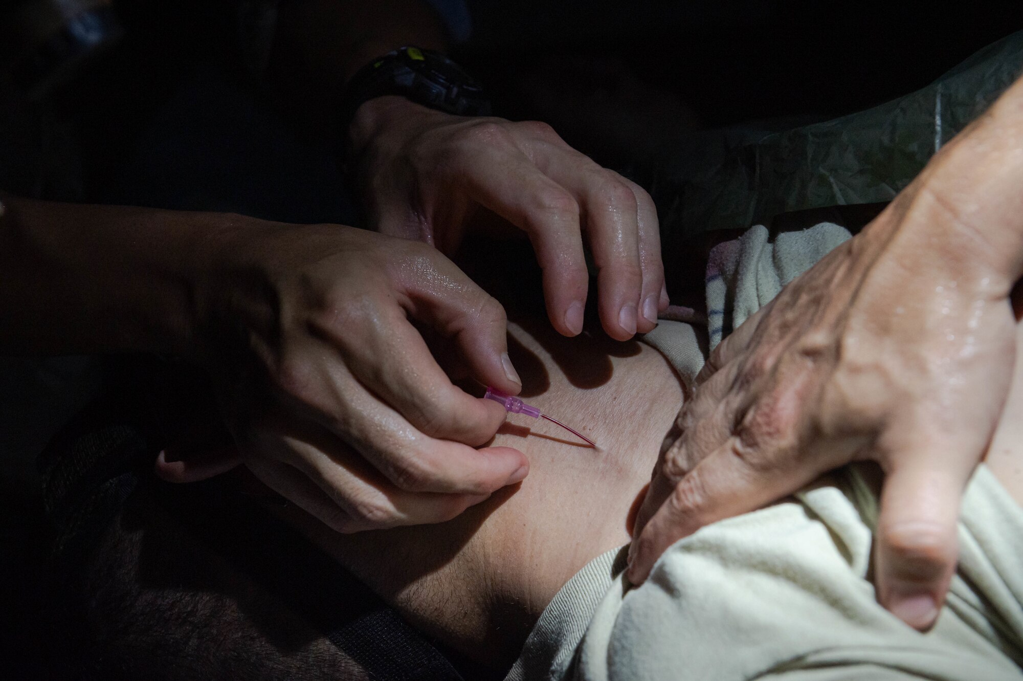 Soldier places a catheter in the neck of a simulated casualty.