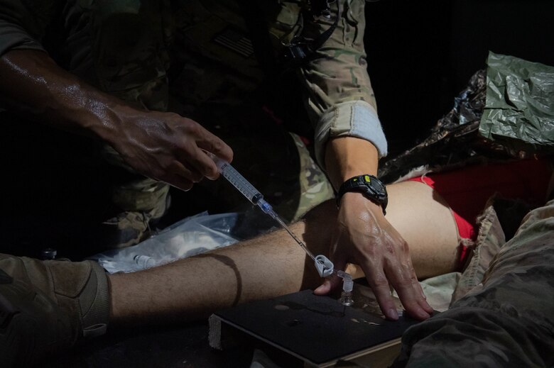 Soldier simulates an intraosseous cannulation on a board.