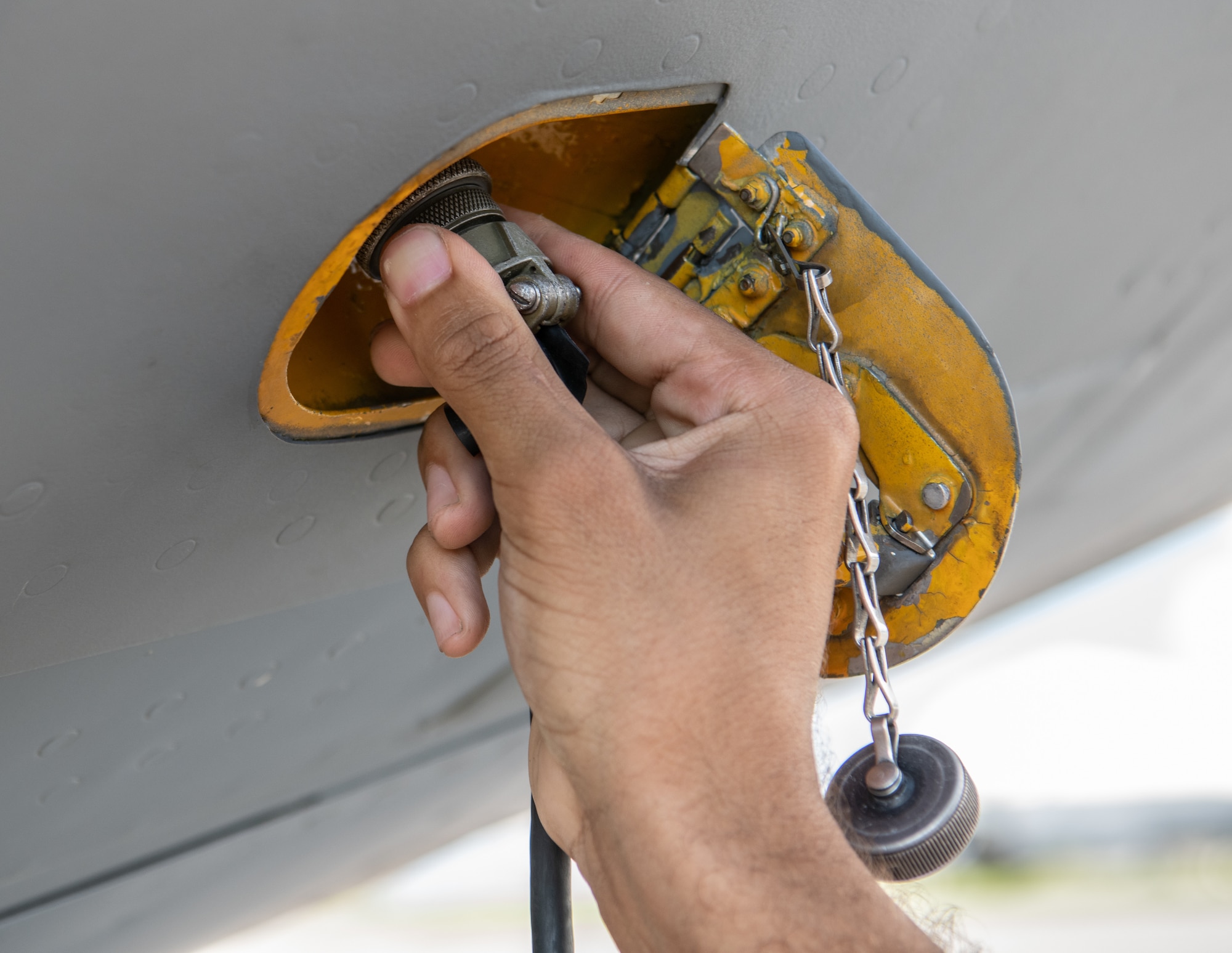 Close up of a hand disconnecting a communication cord from an aircraft.