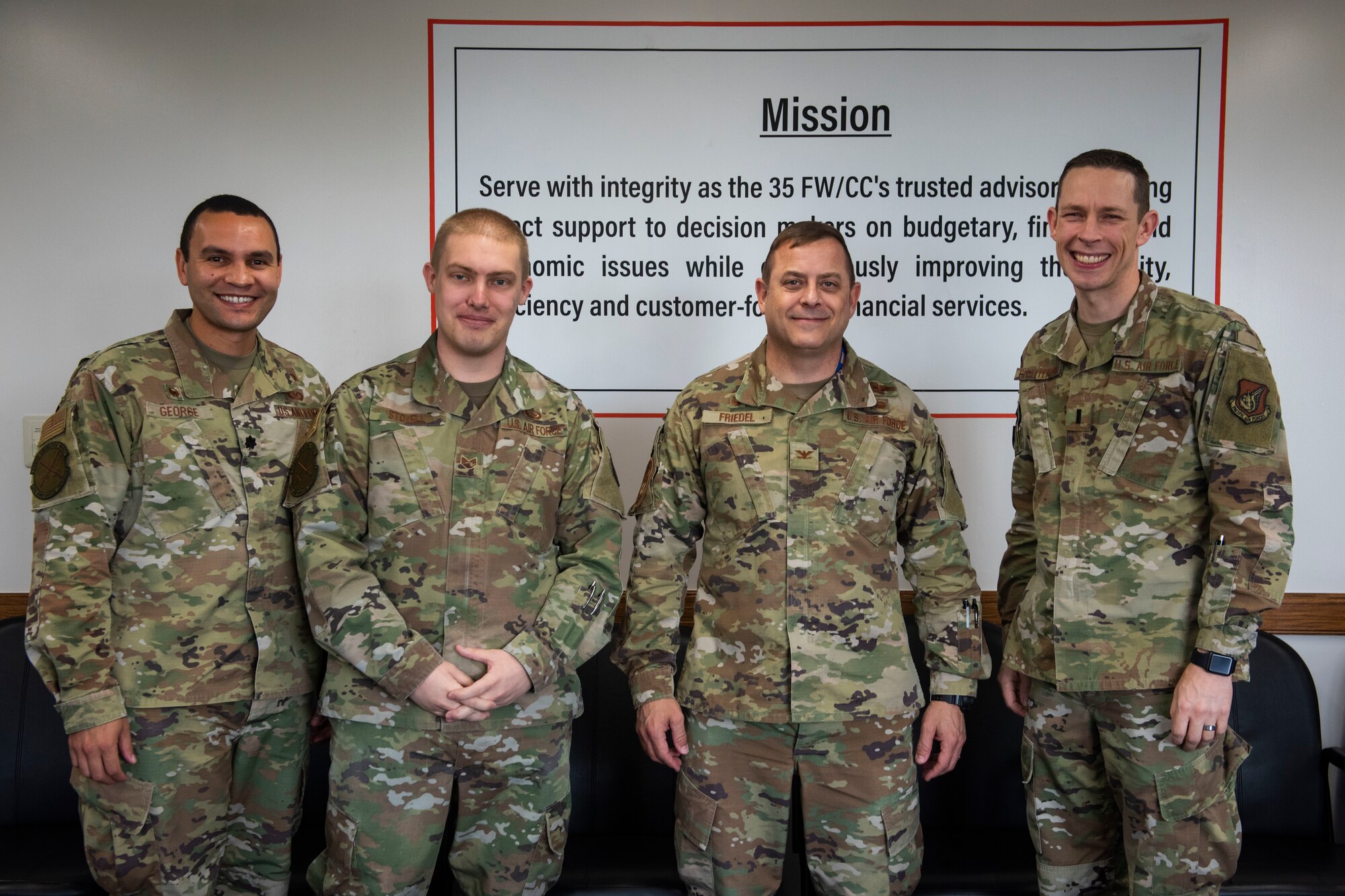 Four men in military uniform stand in an office.