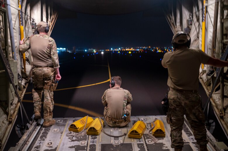 Airmen look out the back of a C-130J