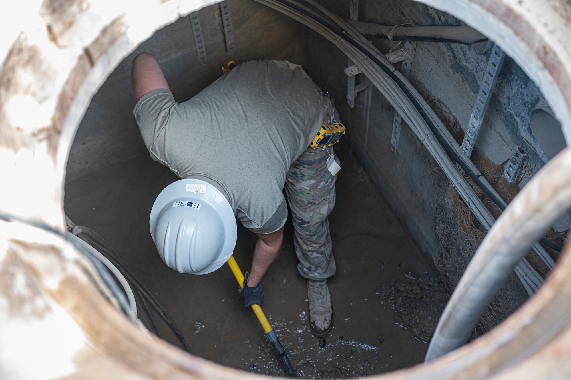 A member of the U.S. Air Forces Central, Air Force Forces A67 Engineering and Installation team clears out a communications maintenance hole at Ali Al Salem Air Base, Kuwait, on Oct. 19, 2021.