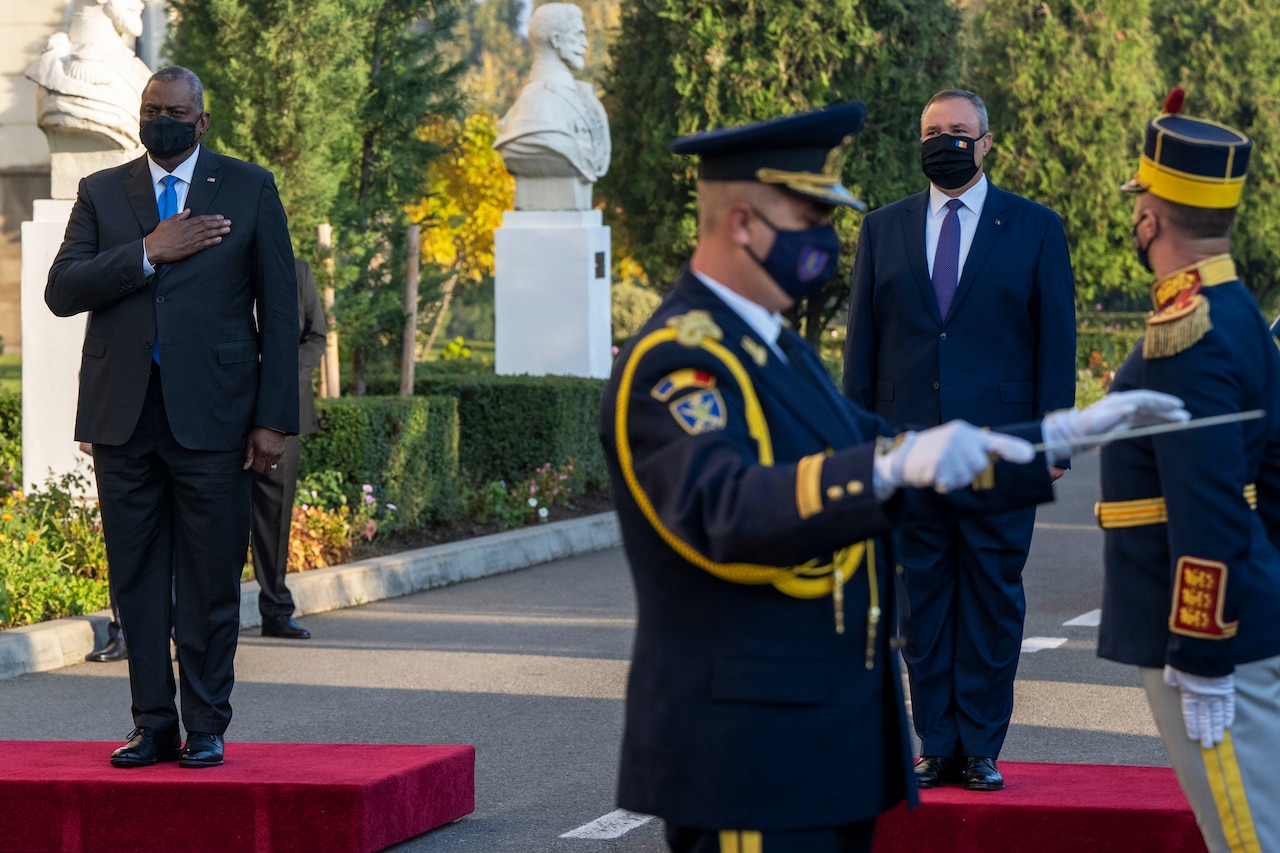 Two men stand at attention during a ceremony.