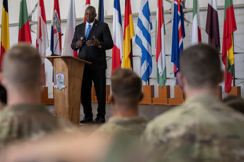 Defense Secretary Lloyd J. Austin III  stands on a stage and speaks with soldiers.