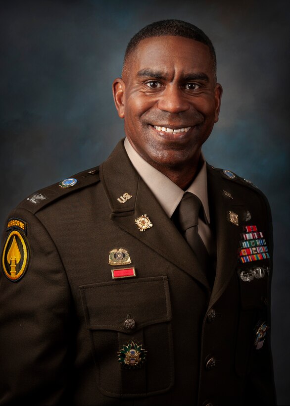 Army Colonel posing in front of flags