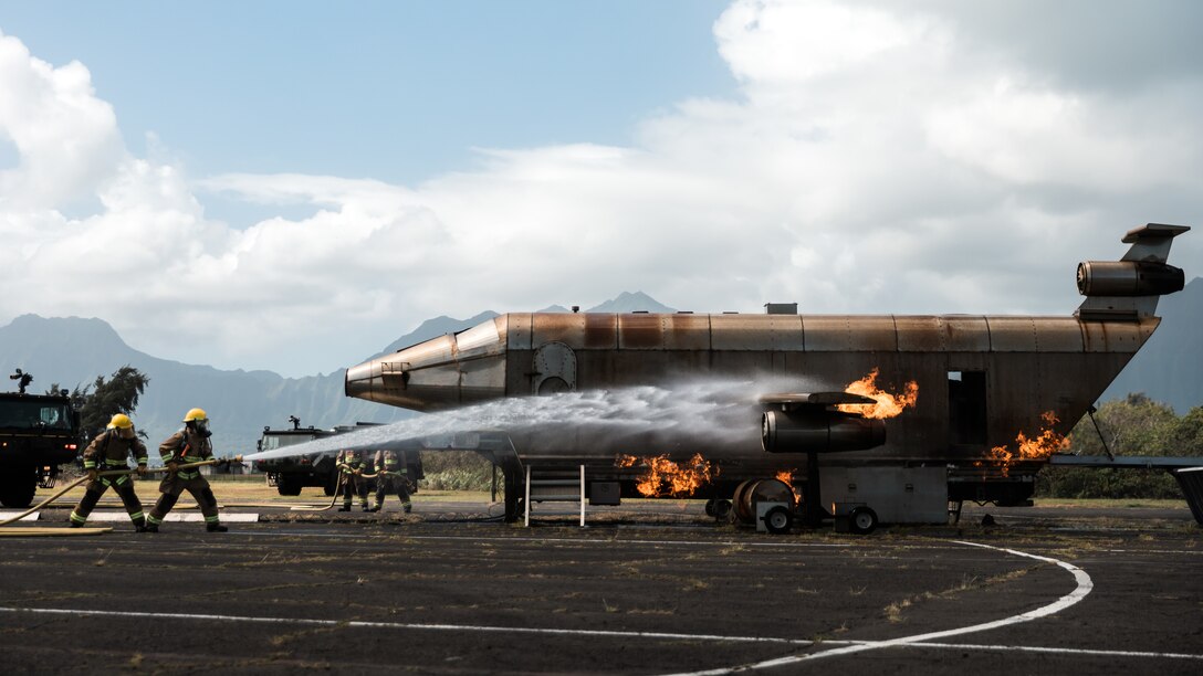 U.S. Marine Corps Cpl. James Leahy, a Weymouth, Mass. native, and Pfc. Dominic Rea, a Manteca, Calif. native, with Airport Rescue Firefighting, Marine Corps Air Station Kaneohe Bay, distinguish a fire during a burning drill event at Marine Corps Base Hawaii, Oct. 9, 2021. The training event focused on proper methods to distinguish small fuel fires in order to progress towards distinguishing larger fires.