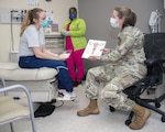 Army Maj. (Dr.) Kayla Jaeger (right), Adolescent and Young Adult Medicine chief, discusses contraception options with patient, Air Force Capt. Jacqueline Wade