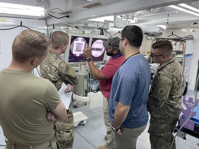 Fernando González-Rodríguez, center, lead electronic technician with the U.S. Army Medical Materiel Agency’s Forward Repair Activity-Medical (FRA-M) team, explains the annual service requirements on a medical imaging system at a Department of Defense Role 3 hospital at the Baghdad Diplomatic Support Center, Iraq. Also pictured, from left to right, are Sgt. Joram Burg and Sgt. Joseph Black, 9th Hospital Center; Eduardo Barraza-Cardenas, biomedical equipment technician with the FRA-M; and Spc. Michael Popinski, 393rd Medical Logistics Company.