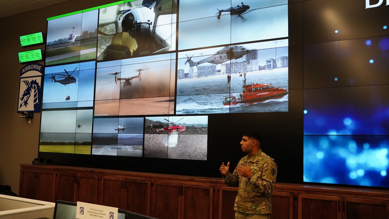 A man stands next to a podium; images of helicopters are on a screen behind him.