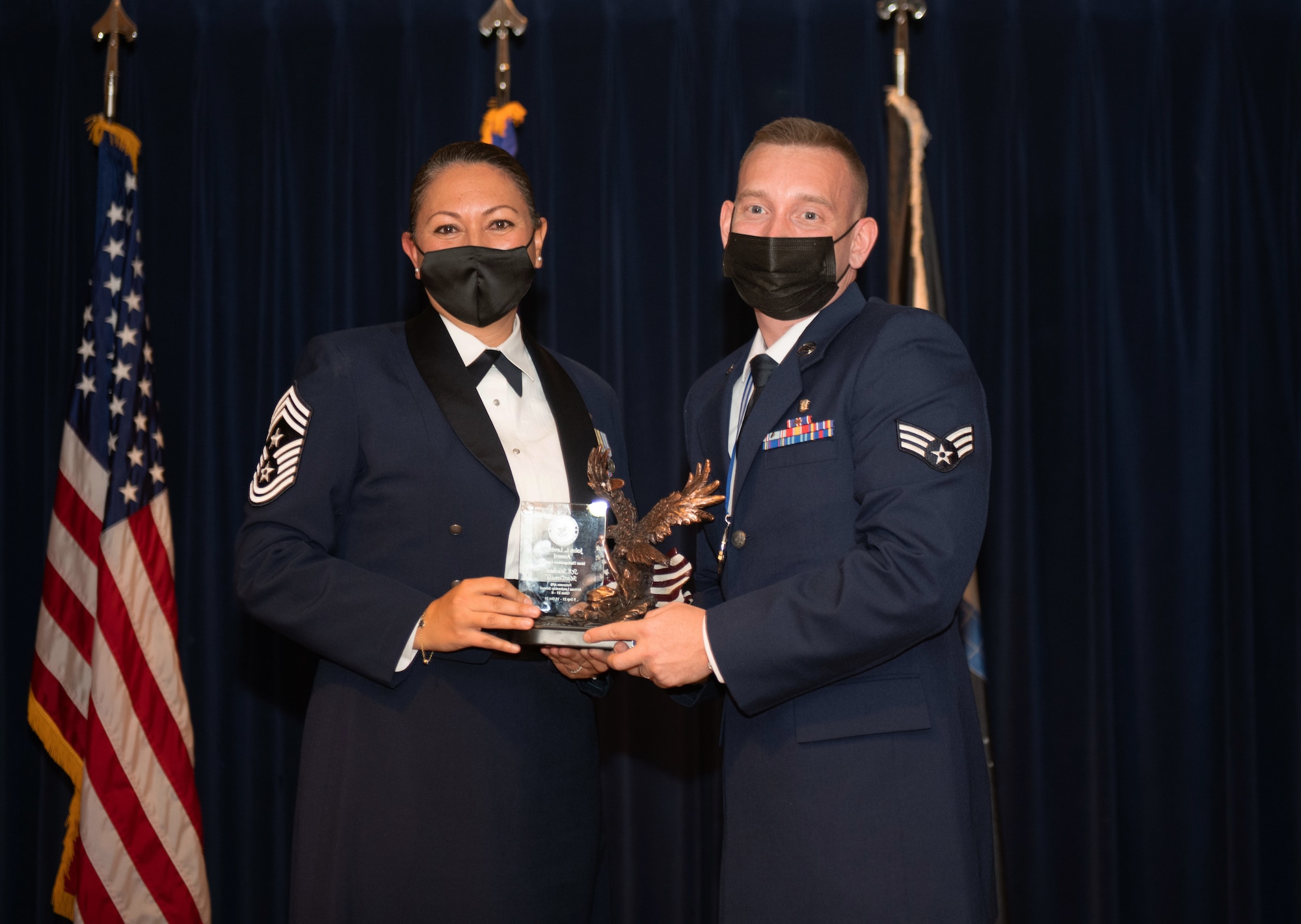 Woman and man hold an award