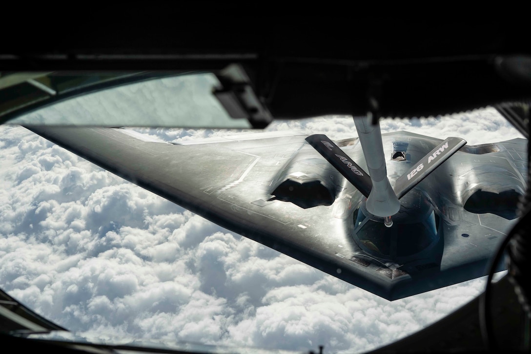 An aircraft receives fuel from another aircraft midair.