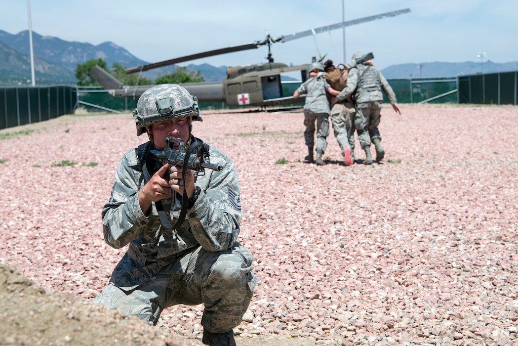 TSgt Jonathan Harris defends other 233rd members as they carry a simulated injured person to an awaiting helicopter during a self-aid/buddy-care exercise.