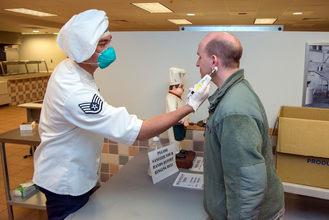 SSgt Shane Materkowski, of the 140th Services Squadron, performs a temperature check on SrA David Rosenberg