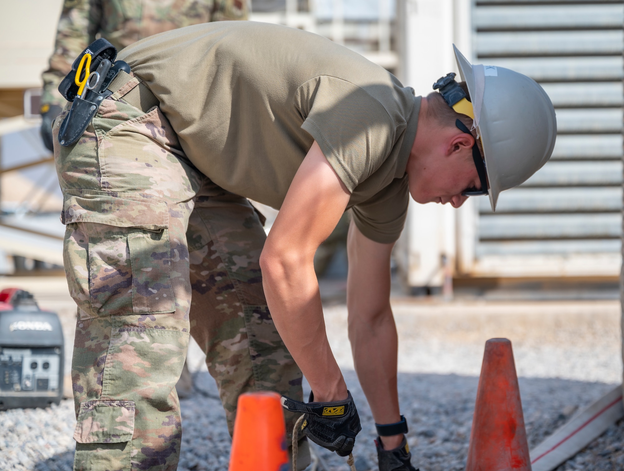 A member of the U.S. Air Forces Central, Air Force Forces A67 Engineering and Installation team lowers equipment into a communications maintenance hole at Ali Al Salem Air Base, Kuwait, Oct. 19, 2021.