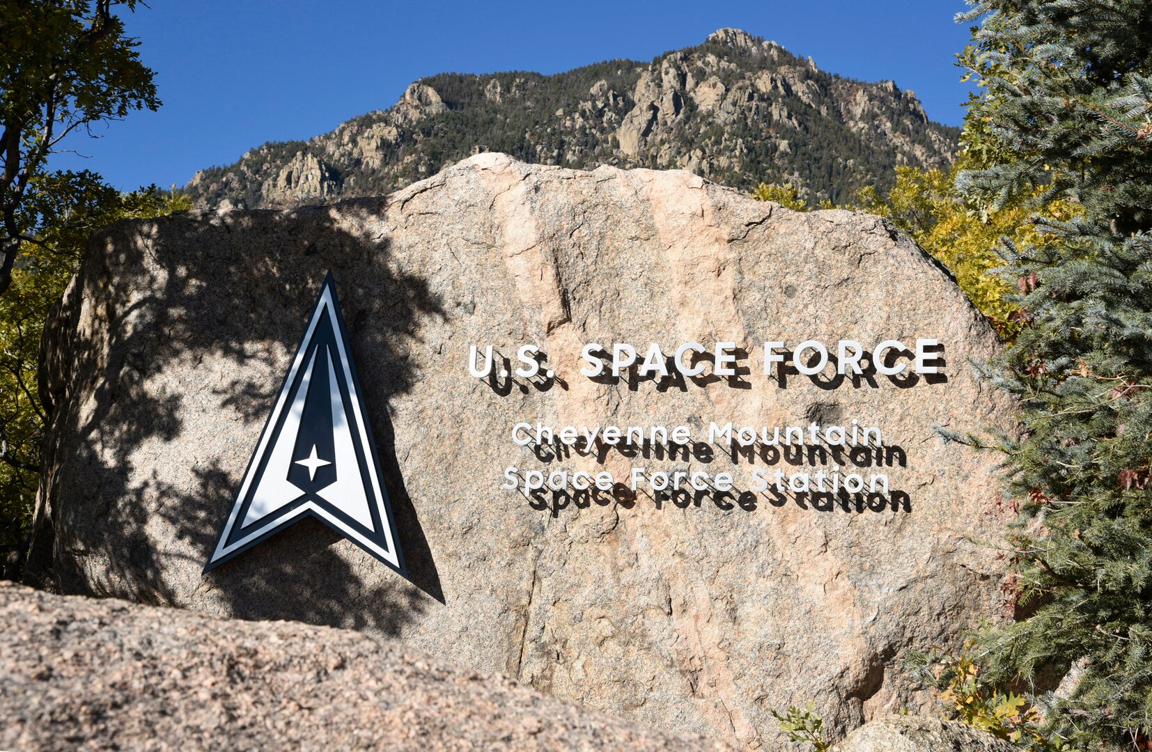 Cheyenne Mountain Space Force Station is written on a boulder next to the Space Force log in the shape of delta symbol.