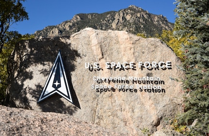 Cheyenne Mountain Space Force Station is written on a boulder next to the Space Force log in the shape of delta symbol.