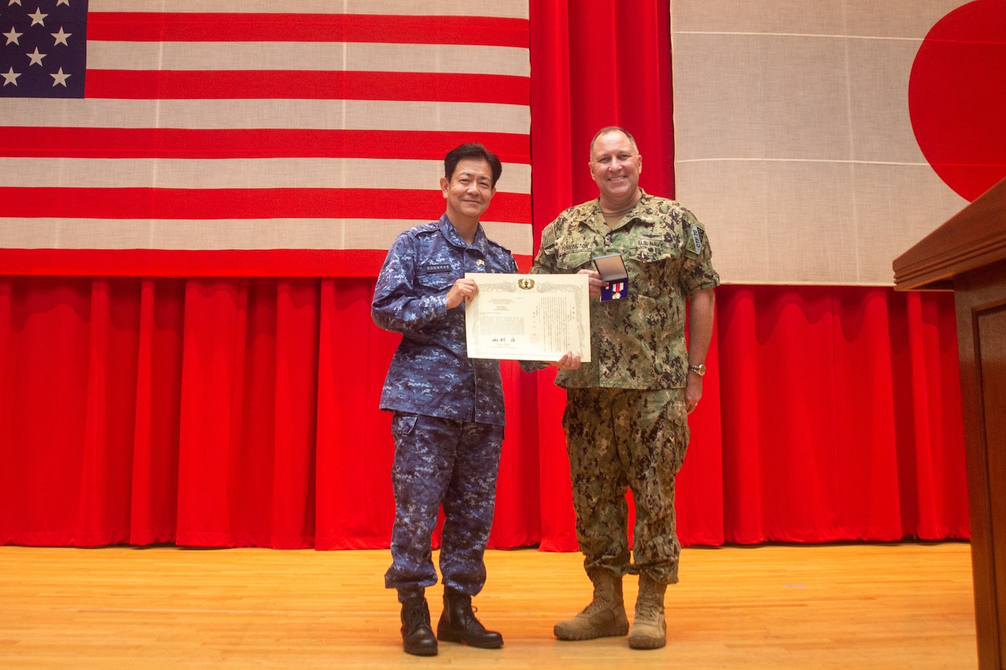 YOKOSUKA, Japan (Oct. 21, 2021) - Rear Adm. Will Pennington receives an award from Vice Adm. SAITO Akira, commander of Japan Maritime Self-Defense Force (JMSDF) Fleet Escort Force during the change of command ceremony for Commander, Task Force (CTF) 70 in the Benny Decker Theater on Yokosuka Naval Base, Oct. 21. (U.S. Navy photo by Mass Communication Specialist 3rd Class Askia Collins)