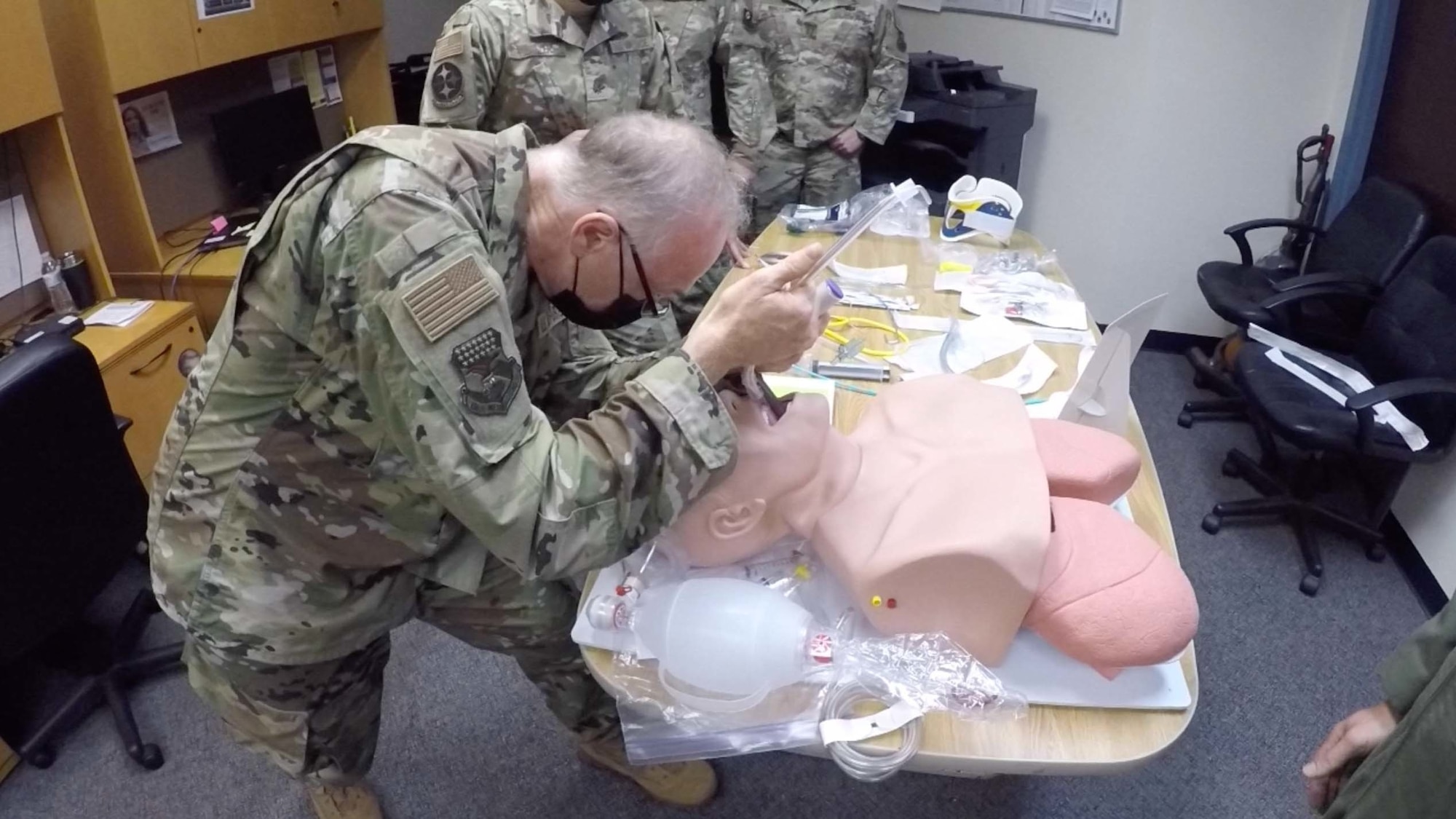 A man in an Air Force uniform intubates a training mannequin.