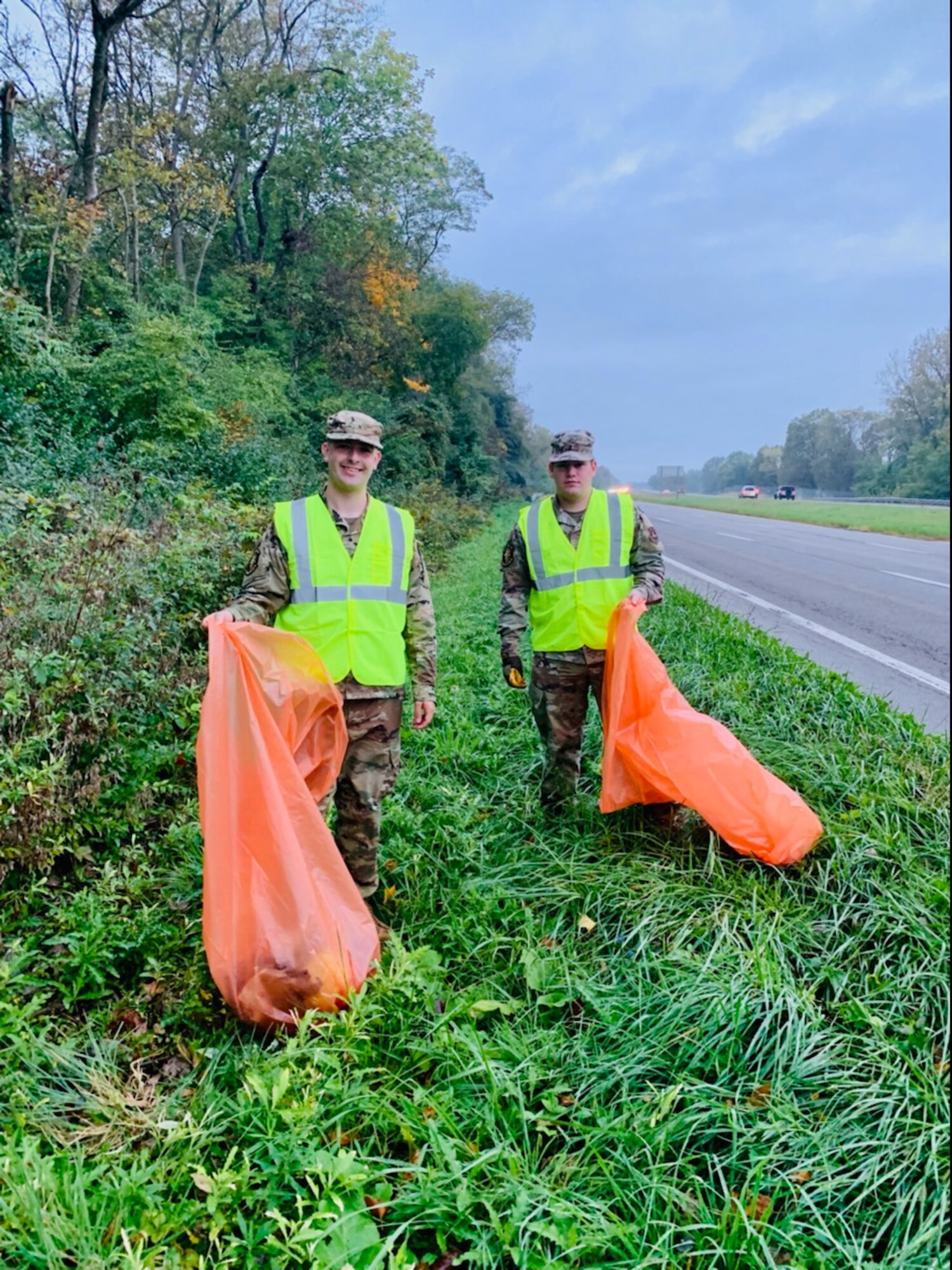 Staff Sgt. Zachary Penrod (left) and Airman 1st Class Matthew Ridenour join together to collect trash Oct. 7 from one side of state Route 444.  (Contributed photo)