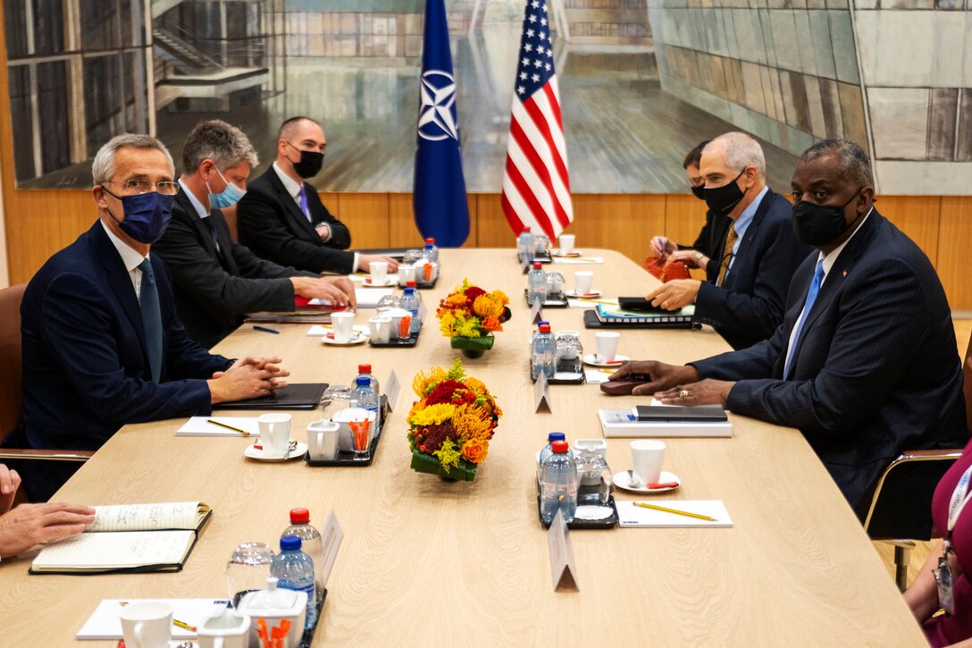 Men wearing face masks sit at a conference table.
