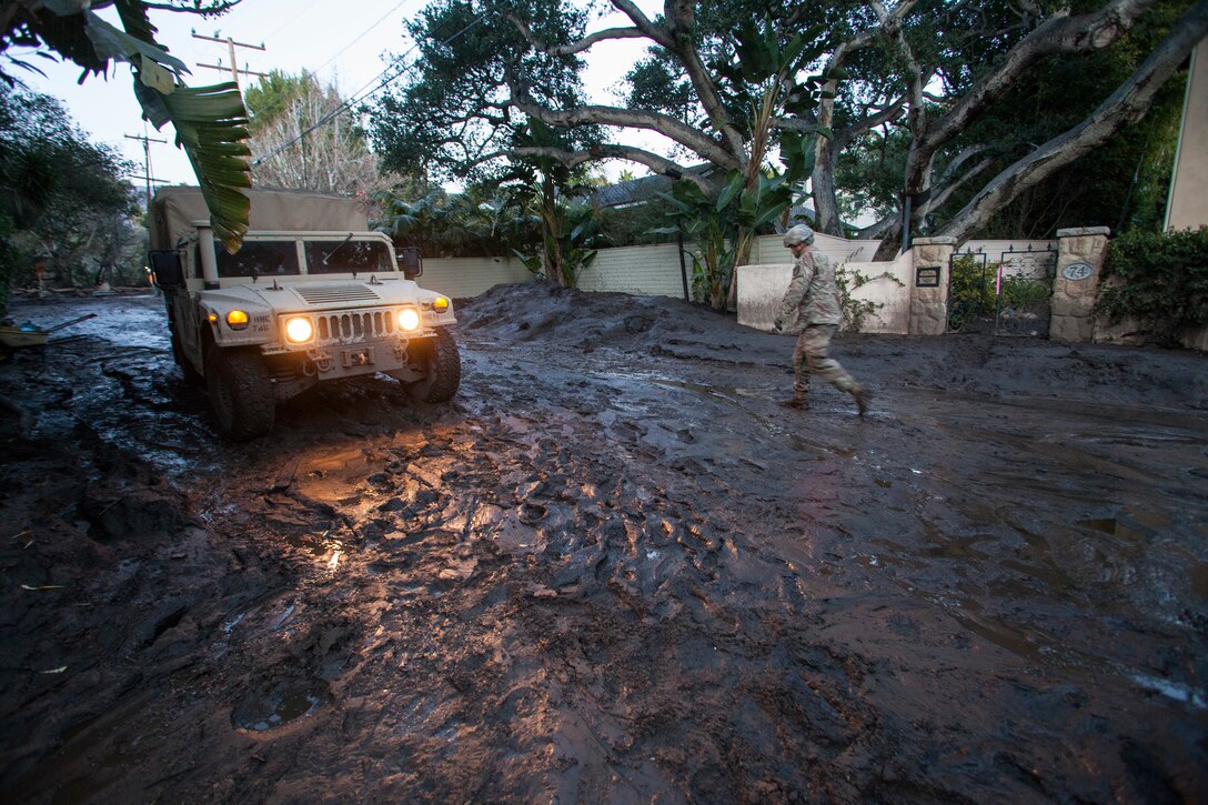 Soldier walks in mud toward a Humvee.