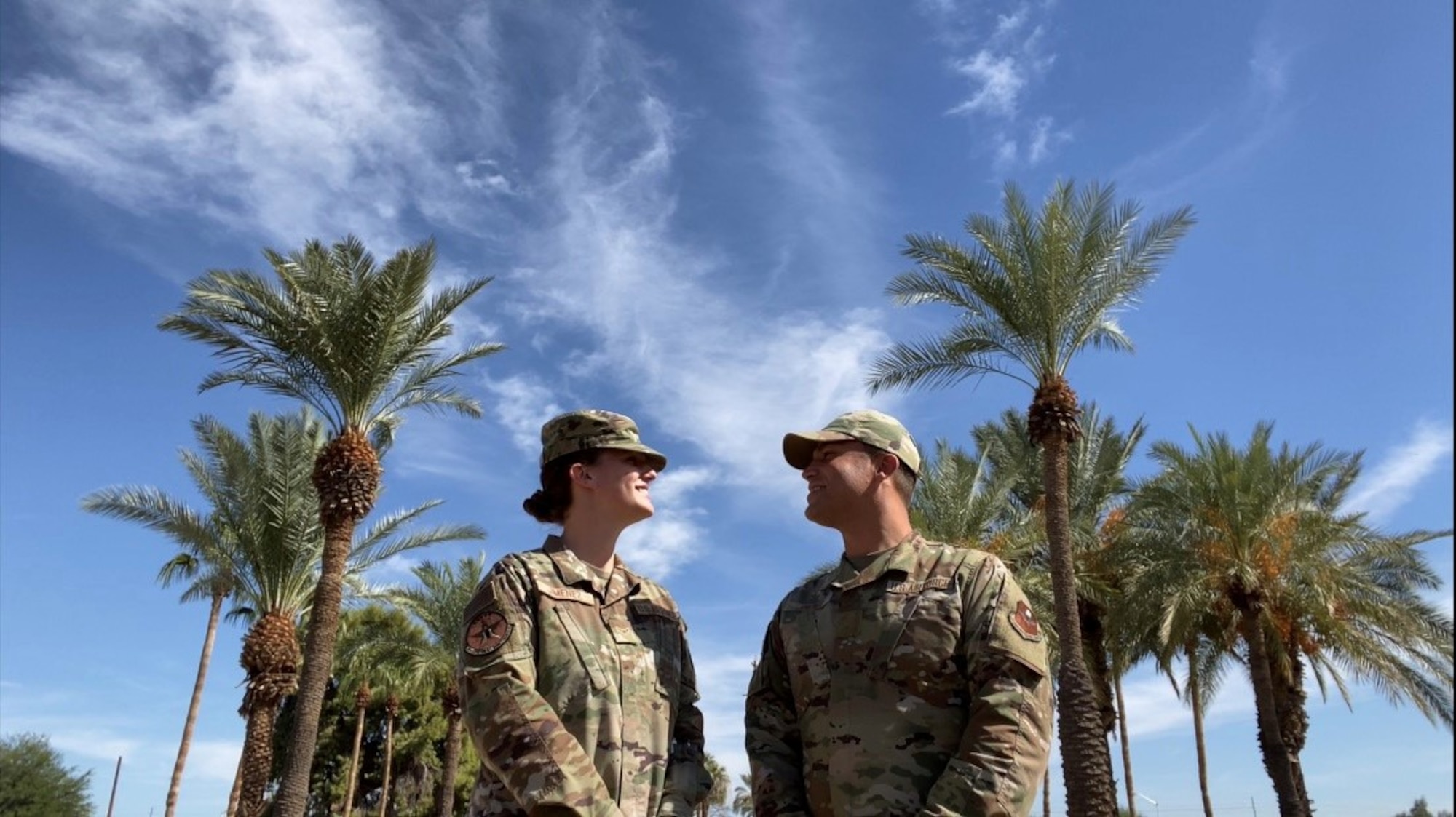 Richard and Jenna Jimenez standing by palm trees.