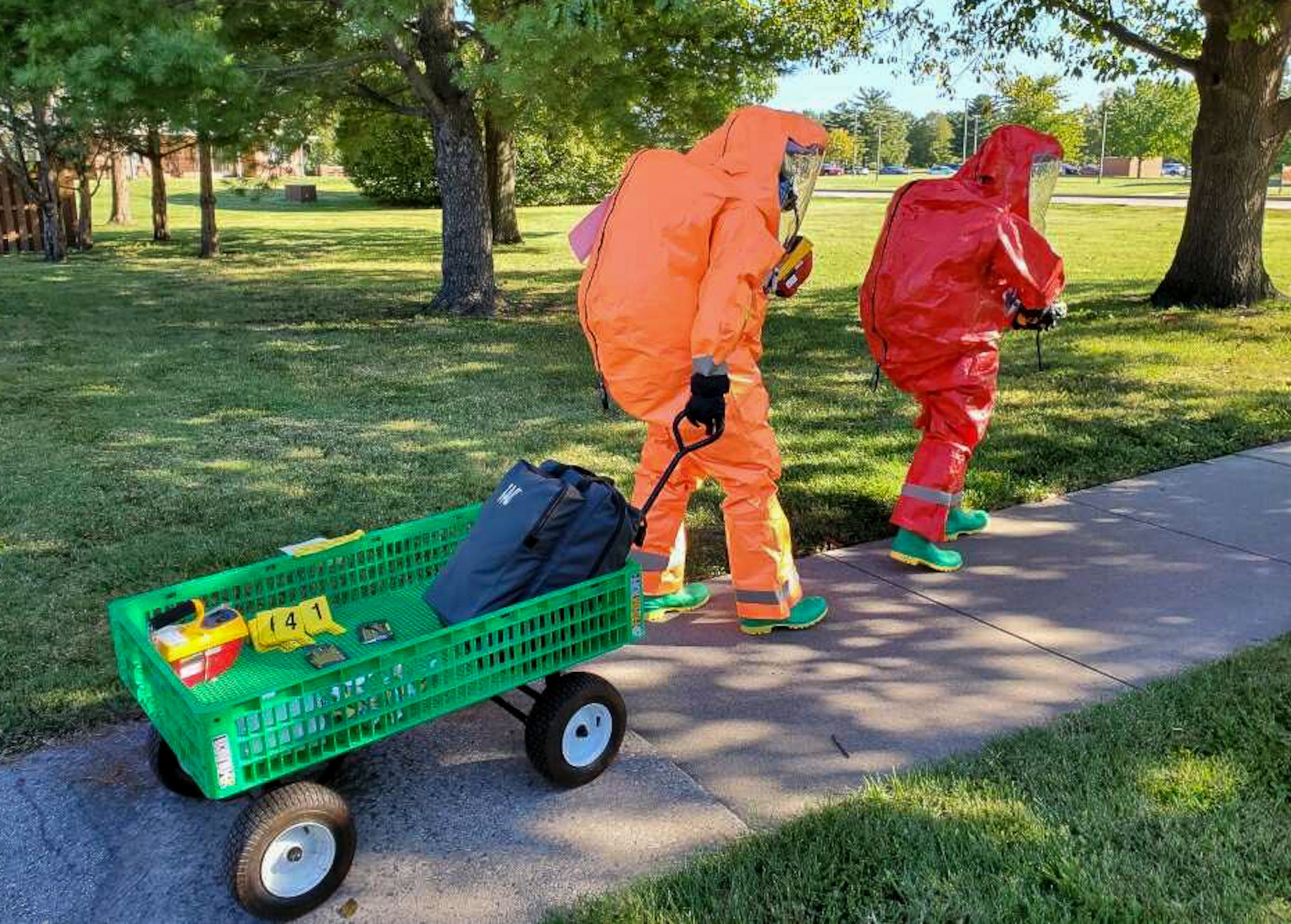 Medics in hazmat gear walk while pulling cart