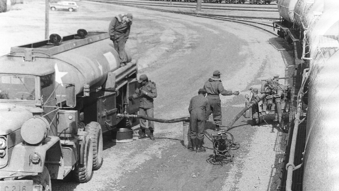 Male soldiers deliver Defense Supply Agency-provided heating oil to Americans during winter 1977.