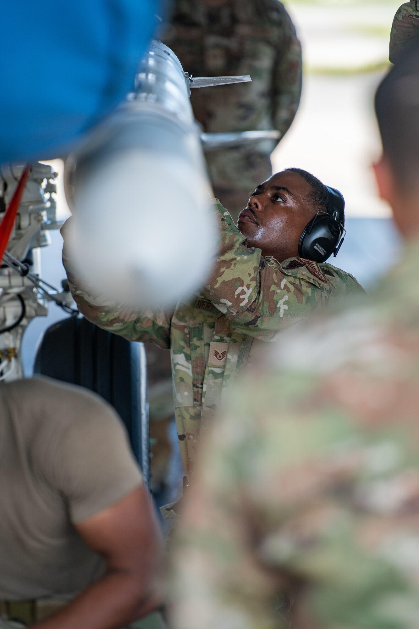 An airman secures a missile underneath a fighter jet