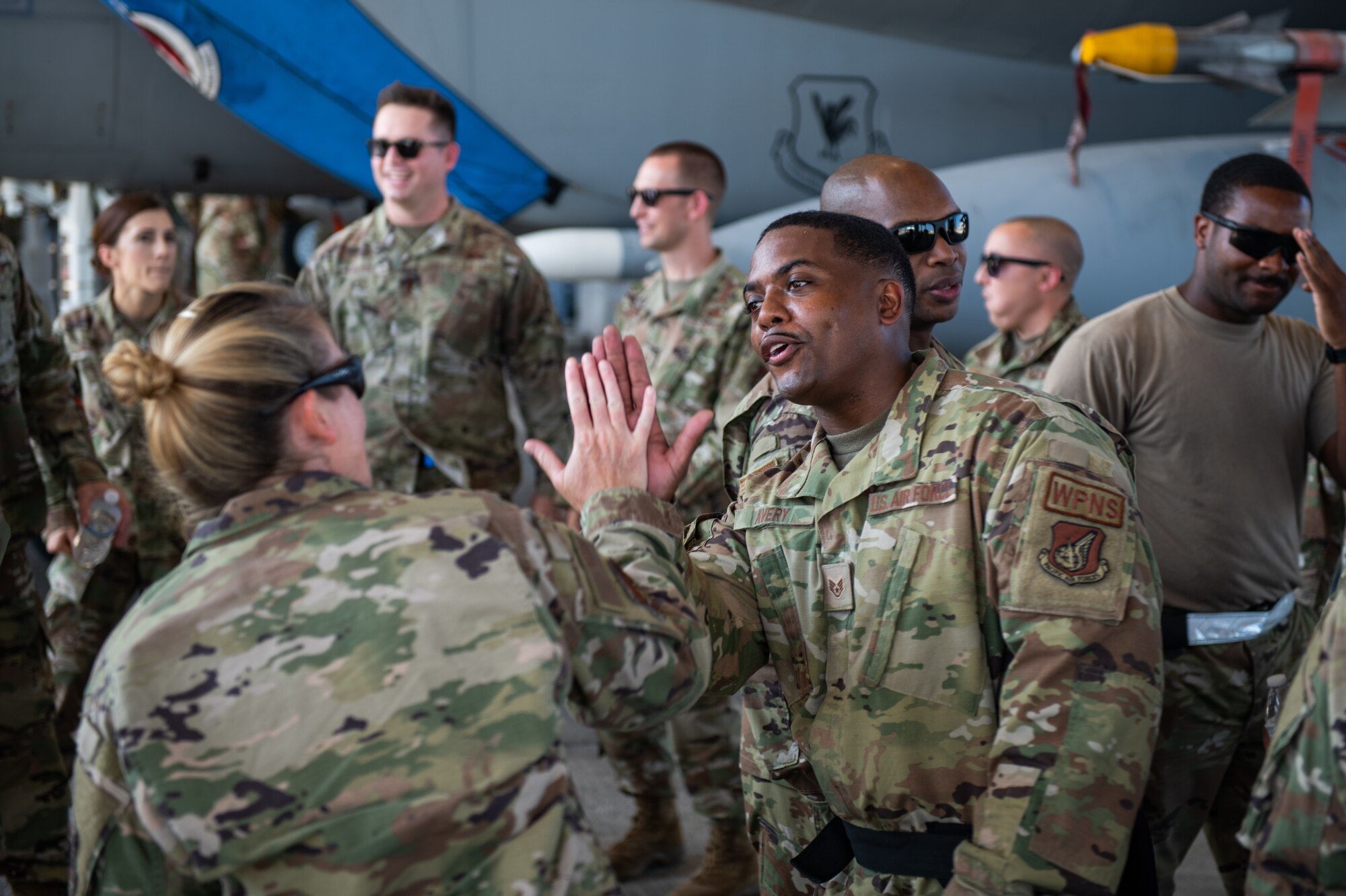 Two Airmen high five in the middle of a group of Airmen after a load competition