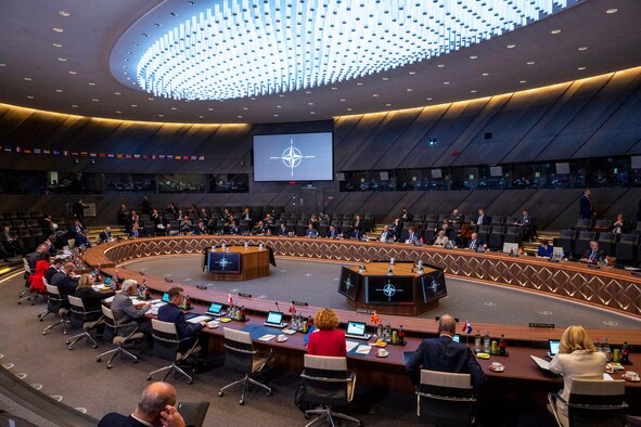 Men wearing face masks sit at a conference table.