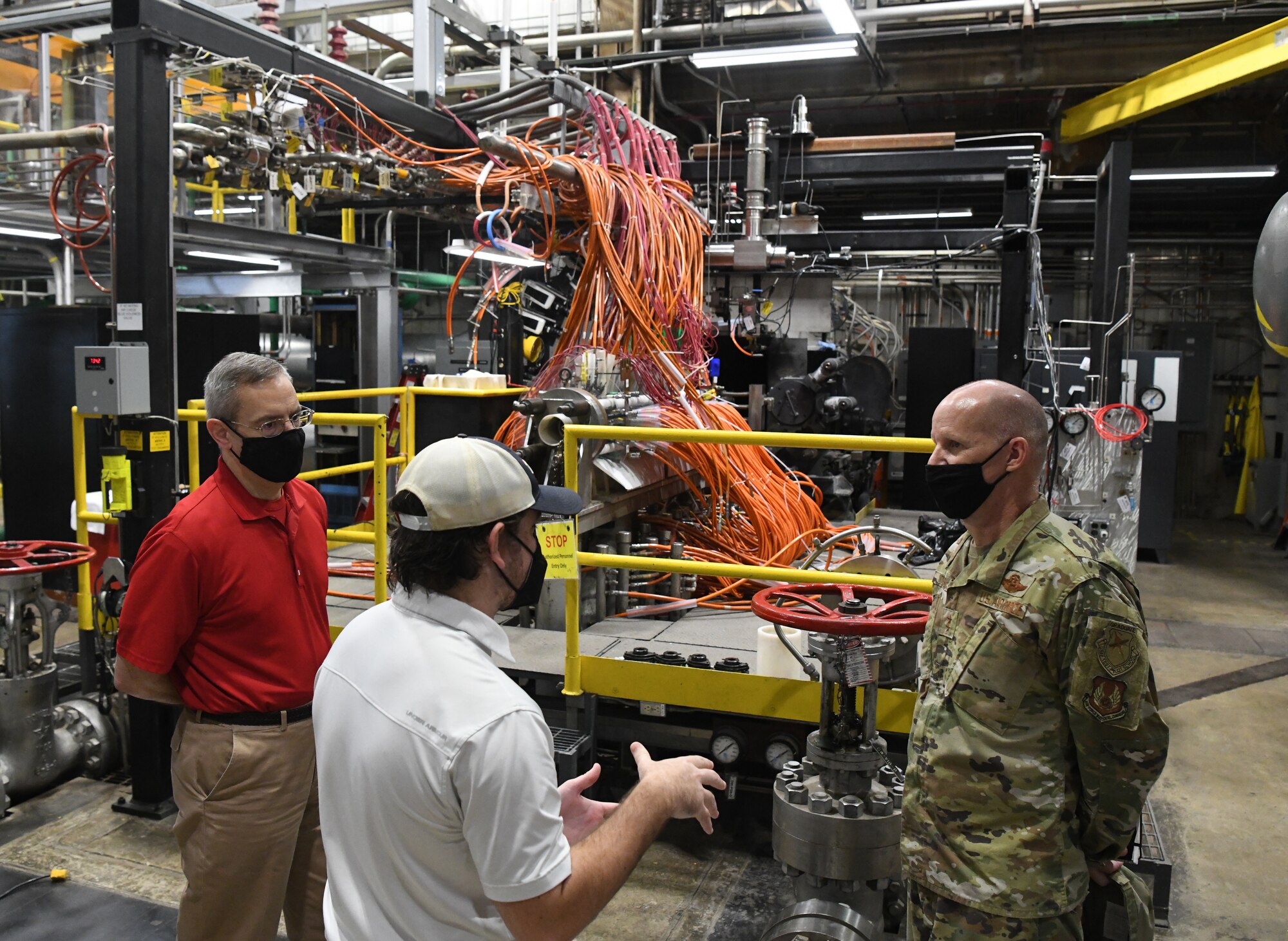 John Hile, center, an Arnold Engineering Development Complex (AEDC) test engineer, speaks with Maj. Gen. Evan Dertien, commander, Air Force Test Center, about the use of arc heaters, such as the one seen in the background, for characterizing and evaluating thermal protection systems at Arnold Air Force Base, headquarters of AEDC, Oct. 13, 2021. Also pictured is Frank Wonder, arcs capability manager. (U.S. Air Force photo by Jill Pickett)