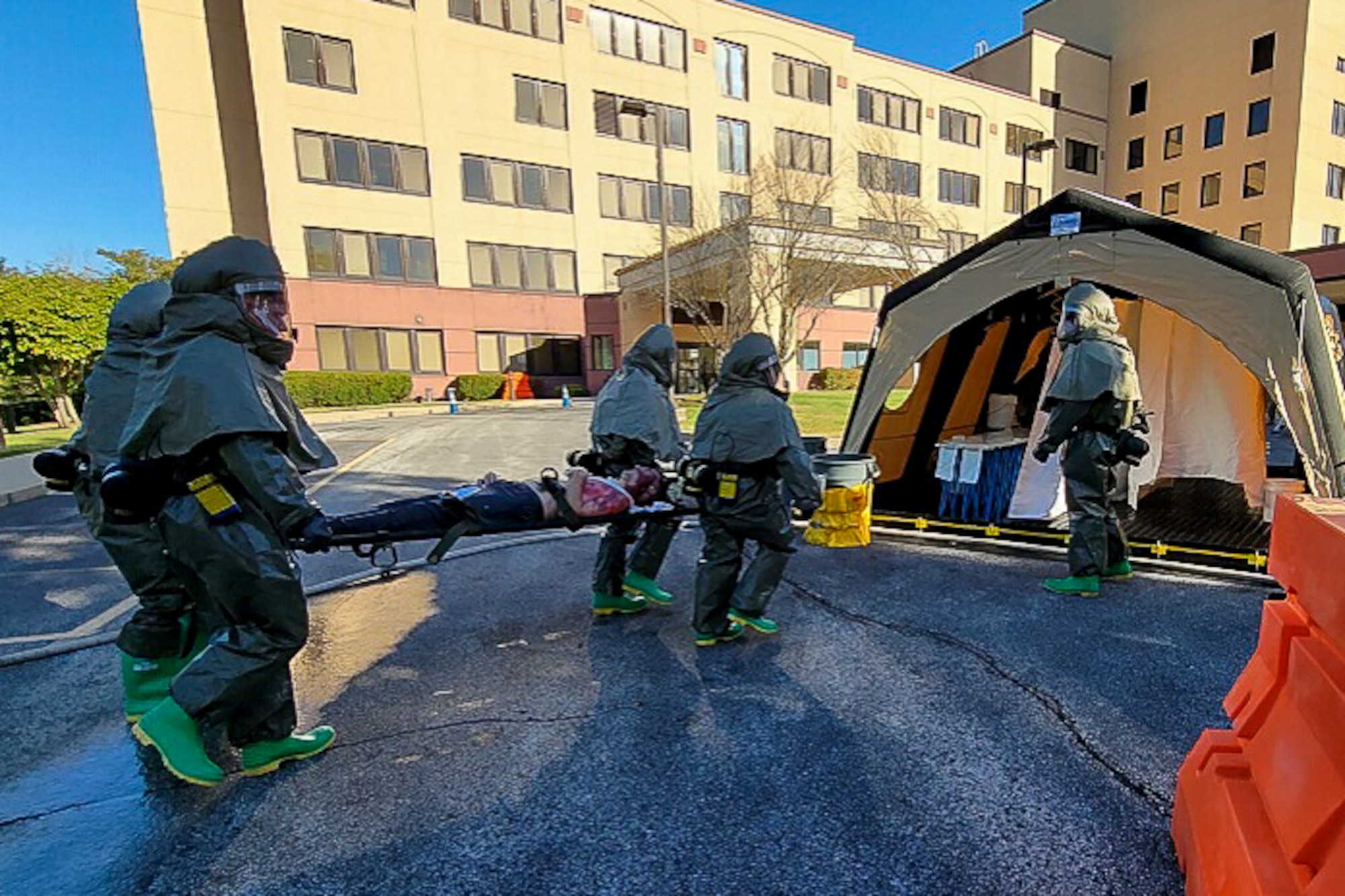 Medics in hazmat gear carry patient on stretcher