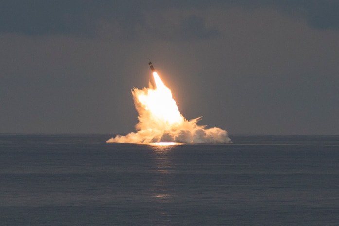 A missile launches from a ship at sea.