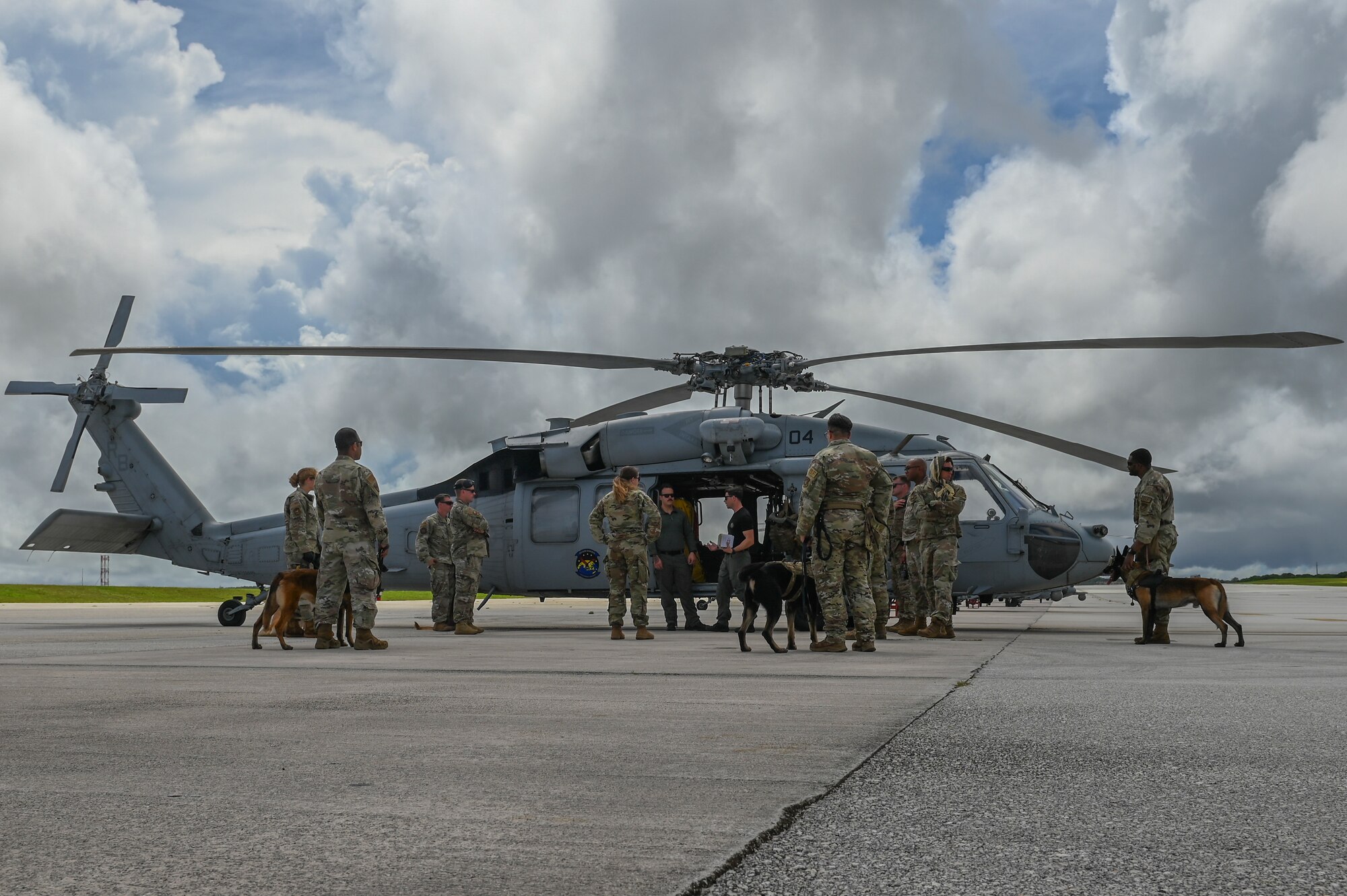 A helicopter surrounded by Airmen and military working dogs.