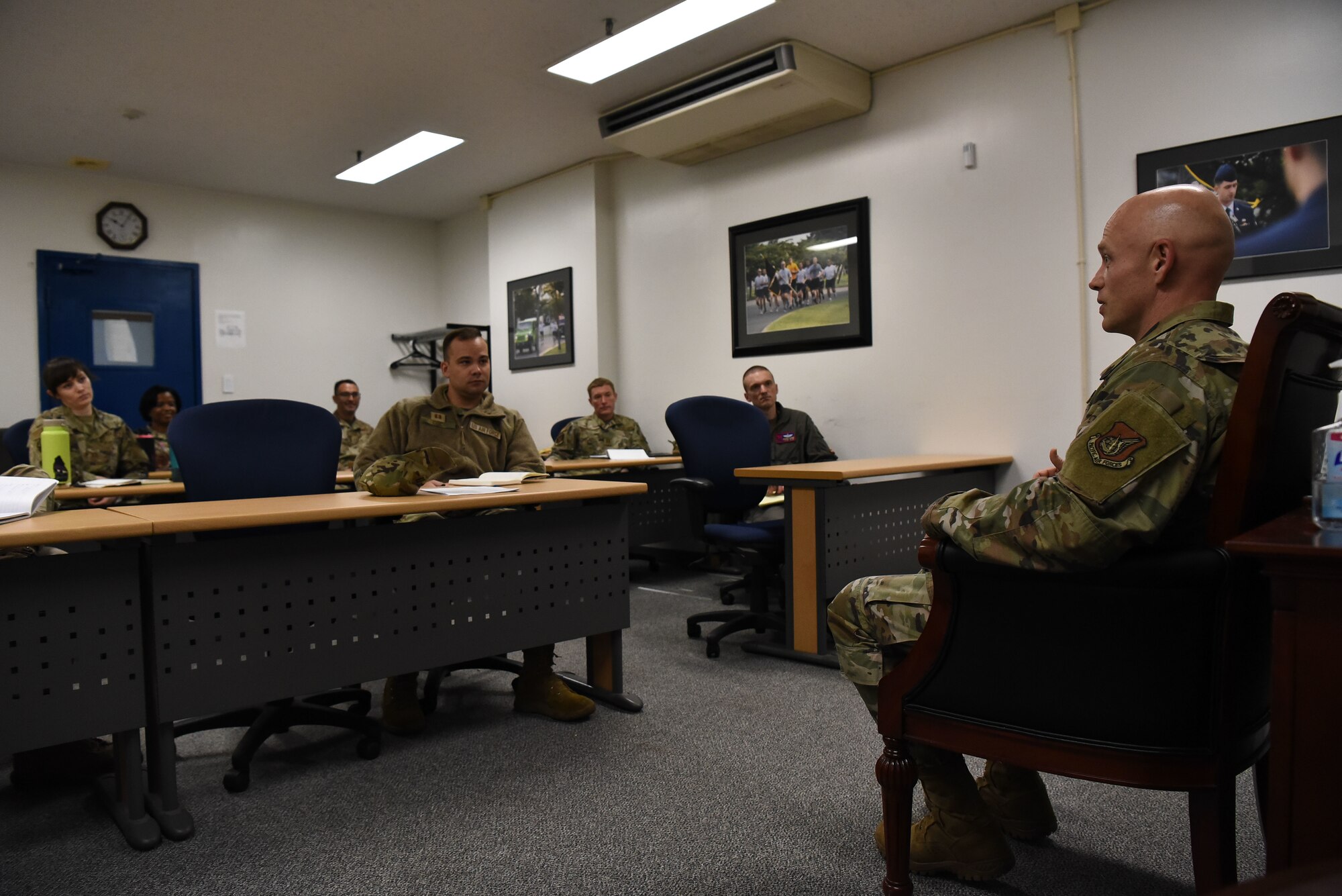 A military member on the right side of the picture looks at a class of military members.