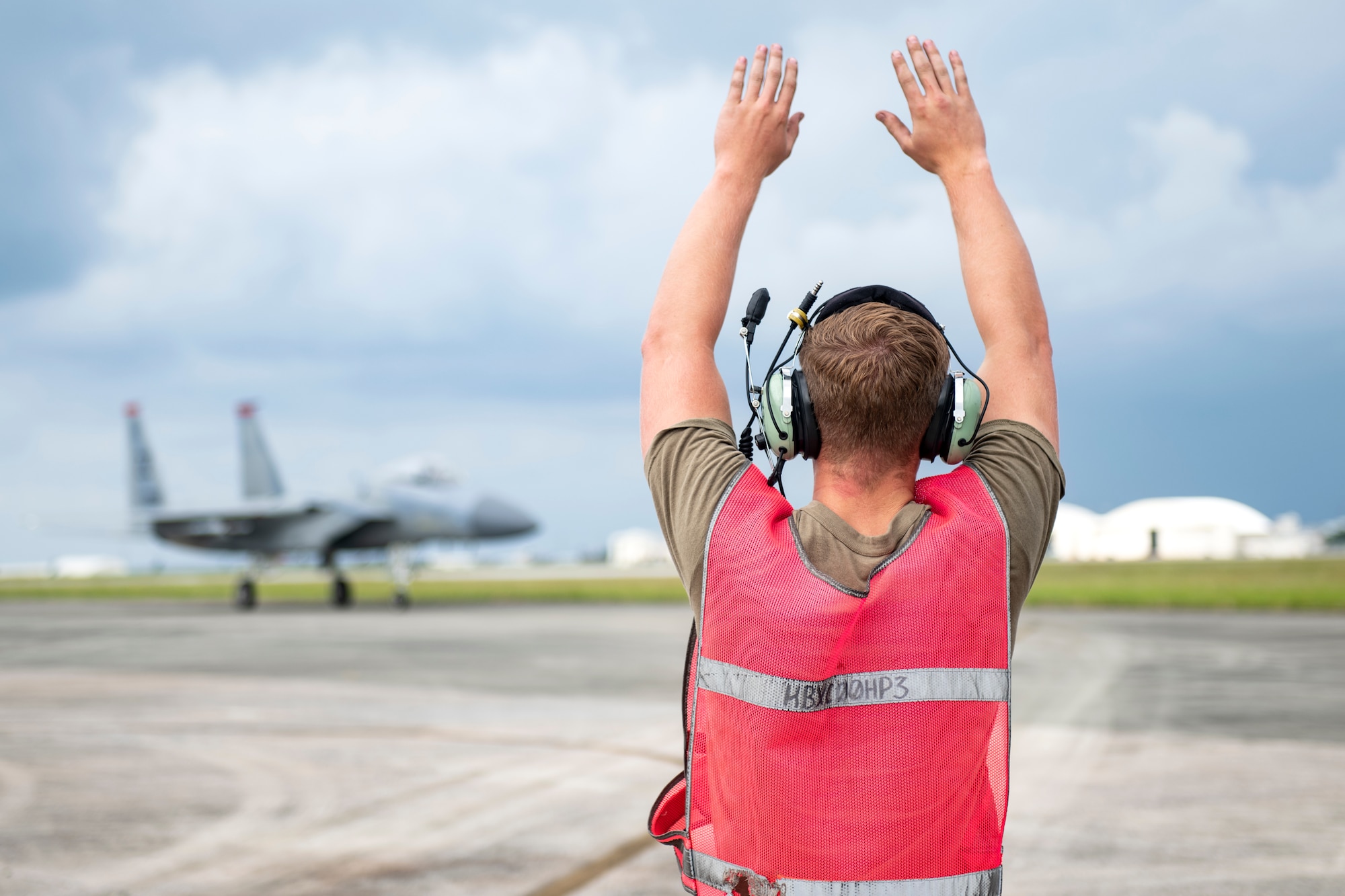 Airman 1st Class Connor Perkins, 67th Aircraft Maintenance Unit assistant dedicated crew chief, marshals an F-15C Eagle onto the apron during a super surge exercise at Kadena Air Base, Japan, Oct. 19, 2021. Surge operations are designed to simulate a fast-paced, deployed combat environment to ensure aircrew and support personnel are always ready to execute missions in defense of the U.S. and its allies. (U.S. Air Force photo by Senior Airman Jessi Monte)