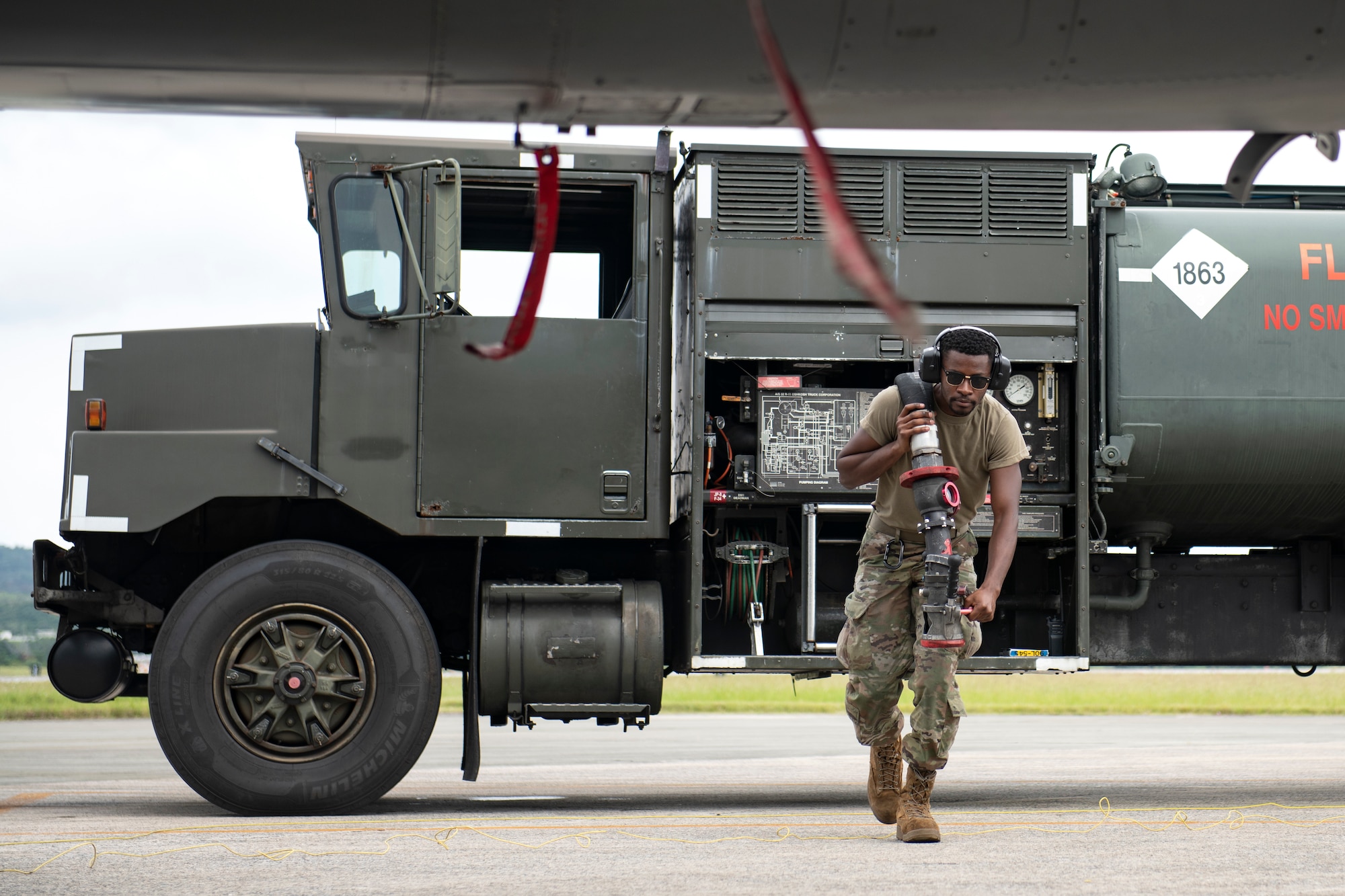 Airman 1st Class Devin Brewer, 18th Logistics Readiness Squadron fuels distribution operator, pulls the fuel hose for hot pit refueling during a super surge exercise at Kadena Air Base, Japan, Oct. 19, 2021. Hot pit refueling reduces the ground time between sorties by refueling active aircraft, enabling maximum training in a shorter time frame. (U.S. Air Force photo by Senior Airman Jessi Monte)