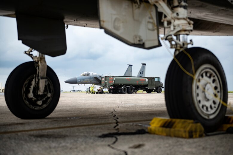 U.S. Air Force F-15C Eagles and R-11 fuel trucks park on the apron for hot pit refueling during a super surge exercise at Kadena Air Base, Japan, Oct. 19, 2021. Hot pit refueling reduces the ground time between sorties by refueling active aircraft, enabling maximum training in a shorter time frame. (U.S. Air Force photo by Senior Airman Jessi Monte)
