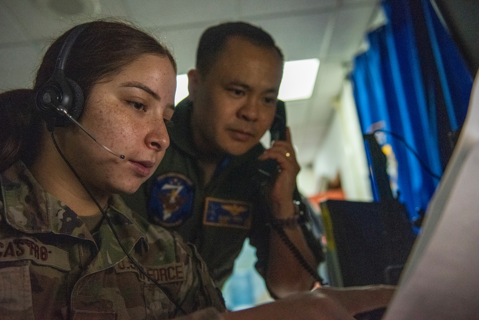 U.S. Navy Lt. Cmdr. Damien “Frito” Le, 607th Air Operations Center joint personnel recovery center (JPRC) director, and U.S. Air Force Senior Airman Alexandra Castro, 607th AOC personnel recovery controller, inspect combat search and rescue (CSAR) intelligence