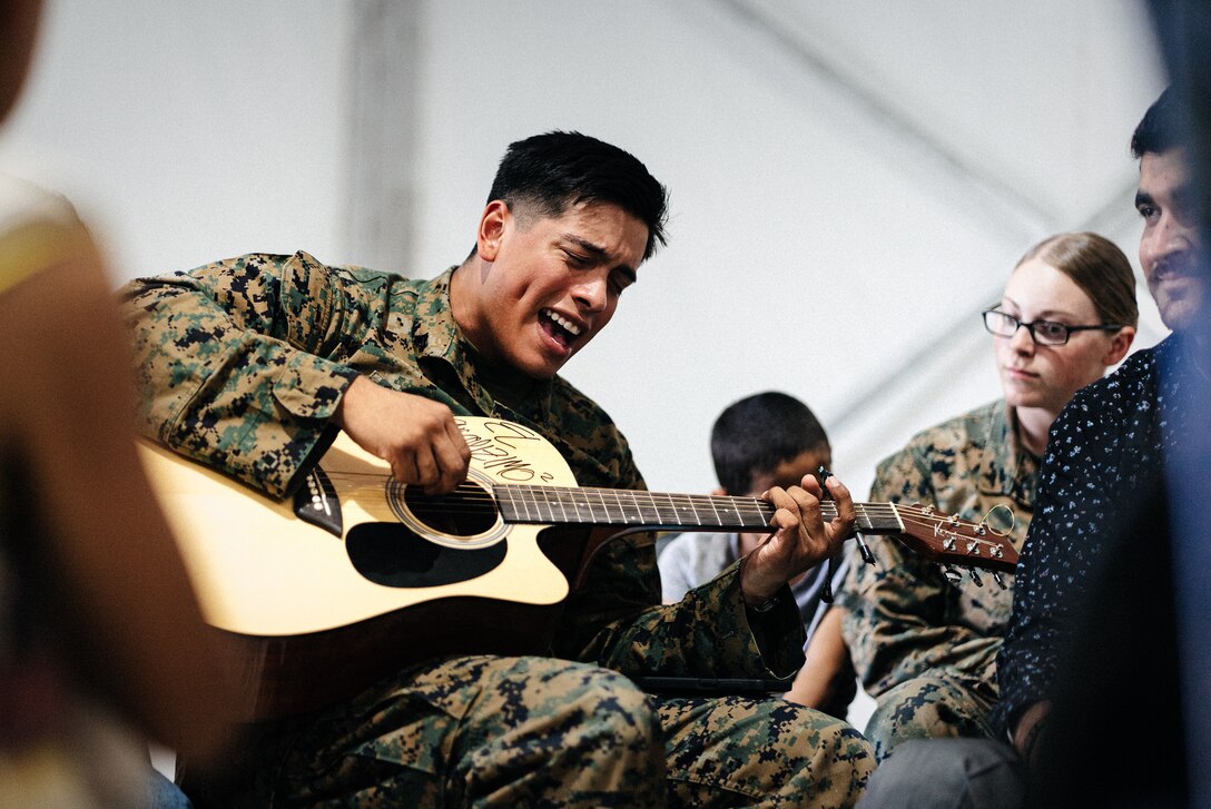 U.S. Marine Corps Cpl. Miguel Sanchez, a radio operator with 3rd Battalion, 6th Marine Regiment, plays his guitar for Afghan individuals on Fort Pickett, Virginia, Oct. 14, 2021. Sanchez began playing the guitar for Afghan individuals to provide entertainment and share his passion for music with them. The Department of Defense, through U.S. Northern Command, and in support of the Department of Homeland Security, is providing transportation, temporary housing, medical screening, and general support for at least 50,000 Afghan evacuees at suitable facilities, in permanent or temporary structures, as quickly as possible. This initiative provides Afghan personnel essential support at secure locations outside Afghanistan. (U.S. Marine Corps photo by Sgt. Corey Mathews)