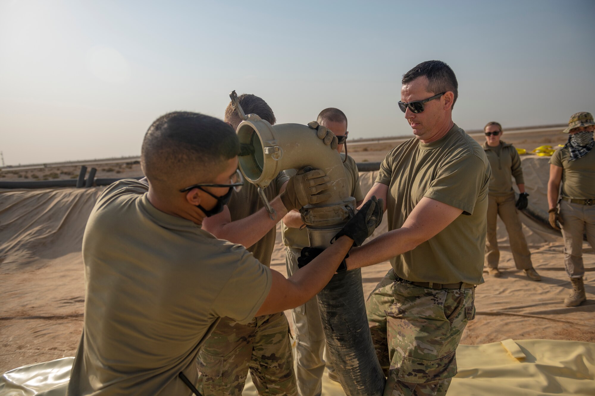 U.S. Airmen with the 332nd Logistics Readiness Squadron attach hoses to a collapsible fabric tank