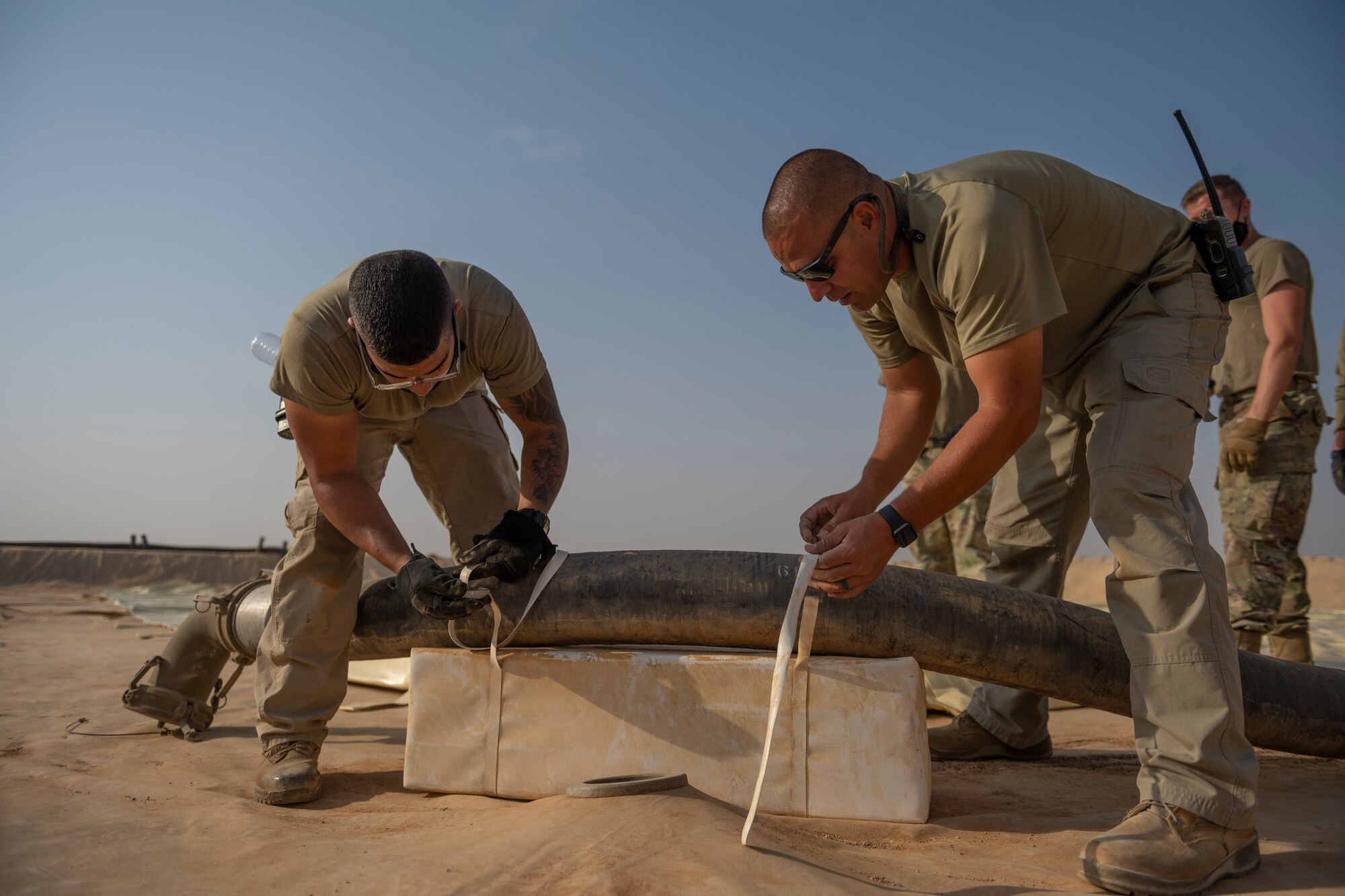 U.S. Airmen with the 332nd Logistics Readiness Squadron attach hoses to a collapsible fabric tank