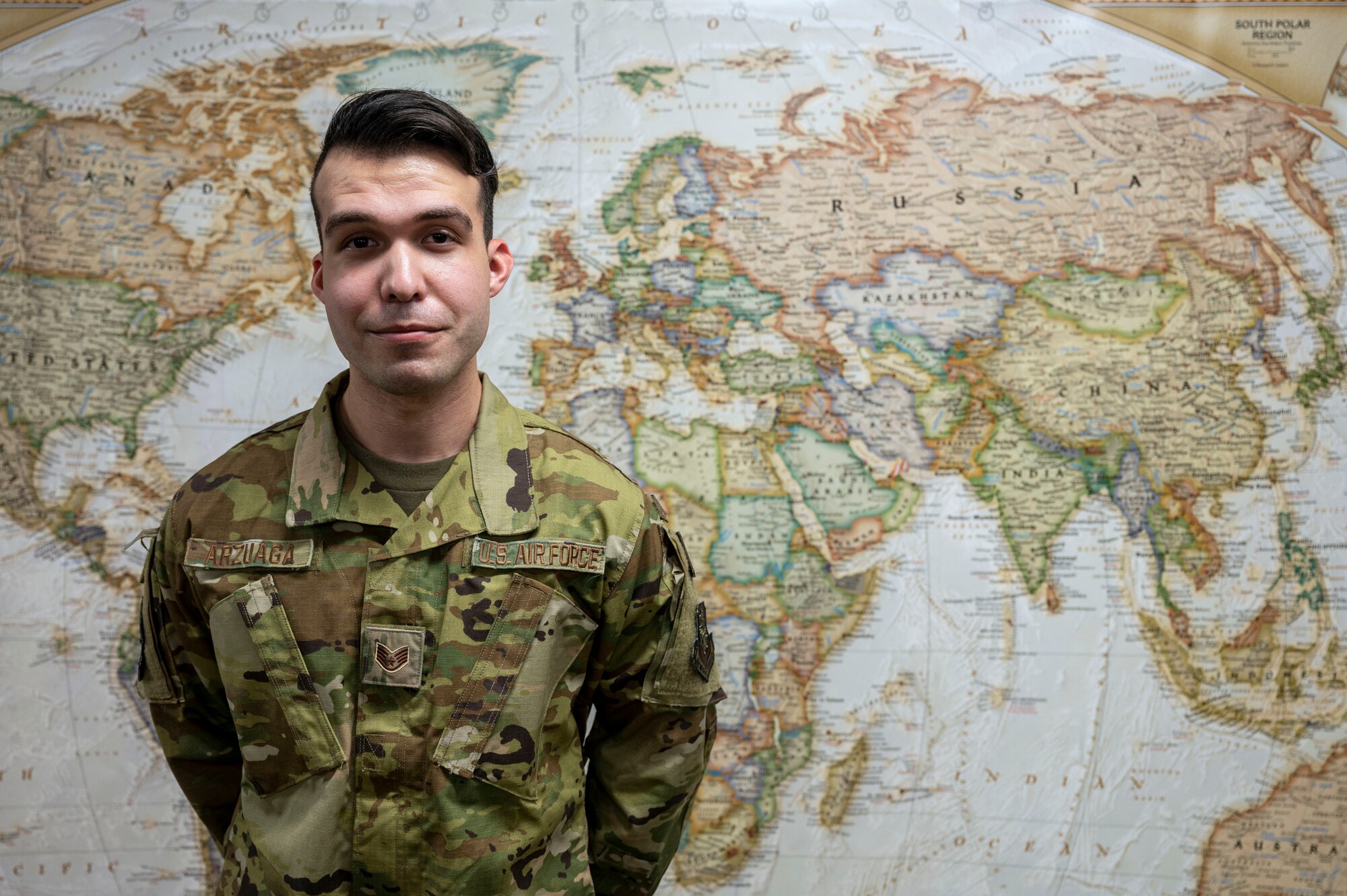 An Airman stands in front of a map.